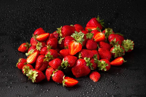 A hill of red Strawberry with water drops on a dark background close-up. Useful dietary product.
