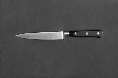 Kitchen knife with a black handle on a black background. Large knife on a dark background. Kitchenware. Knife with a wide blade.