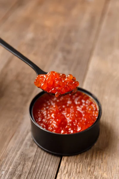 Roter Lachskaviar Einer Offenen Schwarzen Blechdose Und Ein Schwarzer Löffel — Stockfoto