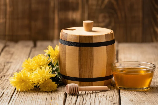 木桶中的蜂蜜 透明的碗 木制围裙 木制背景上的黄色花朵 — 图库照片