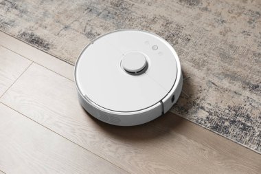 Halıdaki ve laminattaki robot süpürge tozu kaldırıyor. Akıllı ev kavramı, kablosuz temizlik, herhangi bir yüzeyde akıllı bir elektrik süpürgesi..