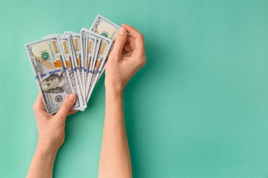 100 dolarlık banknotların çoğu yeşil arka plan manzaralı bir vantilatörde katlanmış ve mesaj için boşluk bırakılmış. Para, banknotlar kadınların elinde. Başarı, iş, zenginlik kavramı.