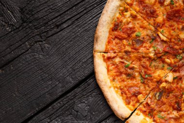 Siyah ahşap zemin üzerinde çeşitli et çeşitleri olan İtalyan pizzası, üst görünüm, kopyalama alanı.