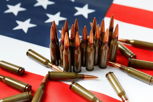 stock image Bullets for firearms, combat army cartridges on the American flag. The concept of lend-lease, the supply of weapons, support, arms sales.