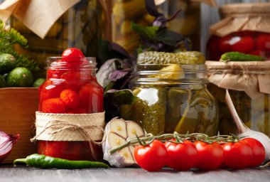 Kavanozlarda konserve kiraz domatesleri ve salatalıklar, taze sebzeler, baharatlar ve salamura için baharatlar ahşap bir arka planda. Sebze turşusu.