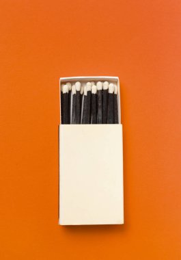 Turuncu arkaplanda siyah bir kibrit kutusu.