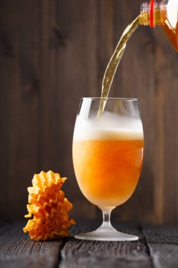 Bira şişeden soğuk, sisli bir bardağa dökülür, patates cipsi yığını koyu ahşap arka planda yakınlarda yatar. Oktoberfest. Bira Festivali