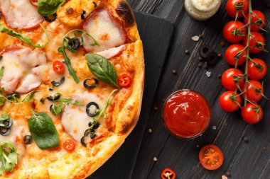 Kurutulmuş et, jambon, zeytin, peynir ve otlar, soslar ve siyah ahşap arka planda siyah taş tabakta taze sebzeler, üst manzara. Geleneksel İtalyan yemekleri.