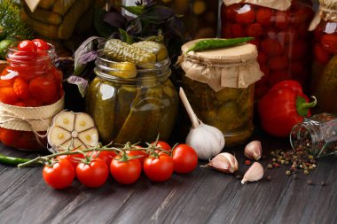 Konserve domates ve salatalık turşusu kavanozlarda, taze sebzeler, baharatlar ve salamura için otlar ahşap arka planda, ev konserveleri
