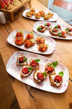 Somonlu bruschetta, güneşte kurutulmuş domates, krem peynir ve bir restoranın masasındaki tabakta bulunan otlar. Restoran yemekleri, İtalyan aperatifleri..