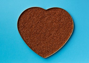 Heart shaped chocolate on a blue background top view with place for text. Chocolate chips in a box in the shape of a heart on a blue background. Valentine's Day. Dark chocolate on a blue background. Love.