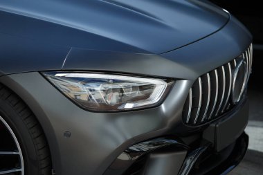 Modern bir arabanın farları ve ön tekerleği yakın plan, zarif bir otomobil tasarımı..