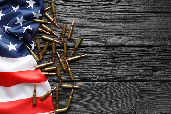 美国国旗 弹药筒 弹药在一个黑色的木制背景 顶部视图 复制空间 武器销售的概念 军事工业 世界军火贸易 图库图片