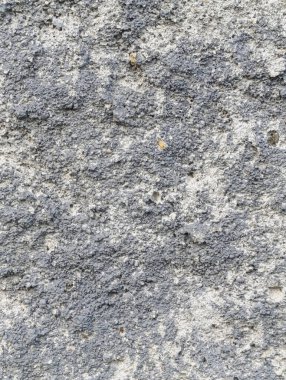 Sert, koyu beton yüzey ve ince detaylar. Koyu renkli, küçük taşlı beton bir yüzeye yakın plan.