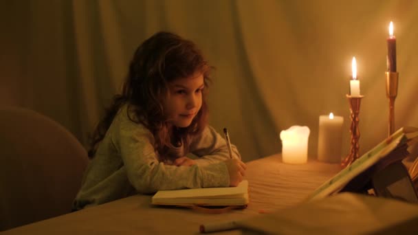 女孩在一间没有电的黑屋子里 烛光下刻苦地写着从底本上写下来的信 — 图库视频影像