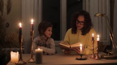 Annesi, askeri saldırganlık nedeniyle karanlık bir dairede mum ışığında kızına bir peri masalı okuyor.