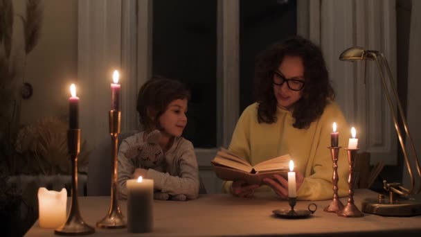 Moeder Leest Een Sprookje Voor Haar Dochter Thuis Bij Kaarslicht — Stockvideo