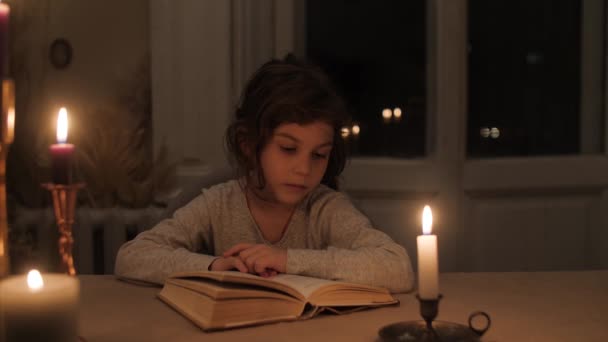 Bir Kız Mum Işığında Kitap Okur Yukarı Bakar Dikkatlice Kameraya — Stok video