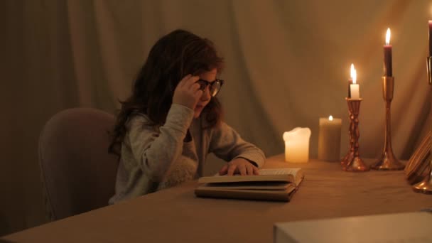 Lány Kezében Tartja Játékbarátját Egy Nyulat Szemüveges Könyvet Olvas Gyertyafénynél — Stock videók