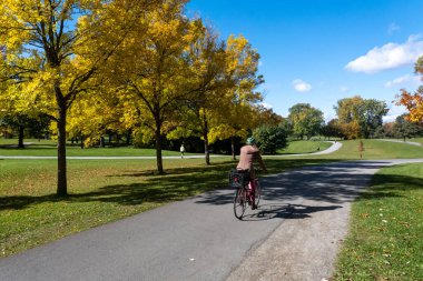 Montreal, Kanada - 10 Ekim 2022: Sonbahar sezonunda Maisonneuve Park 'ta bisiklet süren kadın