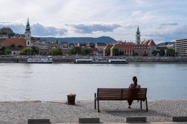 Budapeşte, Macaristan - 1 Eylül 2022: Tuna Nehri kıyısında bir bankta oturan kadın