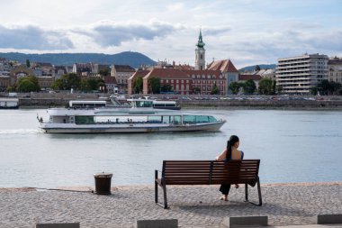 Budapeşte, Macaristan - 1 Eylül 2022: Tuna Nehri kıyısında bir bankta oturan kadın