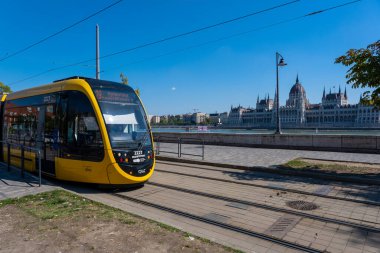 Budapeşte, Macaristan - 3 Eylül 2022: Budapeşte şehir merkezinde, arkasında Macaristan parlamentosu bulunan sarı bir tramvay