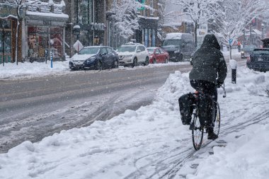 Montreal, CA, 17 Aralık 2022: Kar fırtınası sırasında Saint-Denis caddesinde bisiklete binen adam