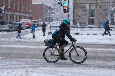 Montreal, CA, 17 Aralık 2022: Kar fırtınası sırasında Mont-Royal Caddesi 'nde bisiklet süren kadın