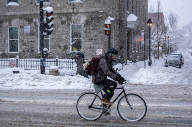 Montreal, CA, 17 Aralık 2022: Kar fırtınası sırasında Mont-Royal Caddesi 'nde bisiklete binen adam