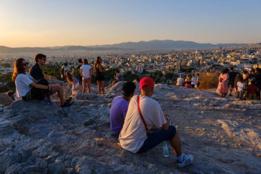 Atina, GR - 29 Temmuz 2023: İnsanlar Areopagus Tepesi 'nde gün batımına bakıyor