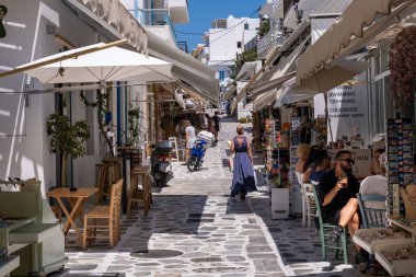 Tinos, GR - 4 Ağustos 2023: İnsanlar Tinos ana caddesinde bir restoranın terasında yemek yiyor