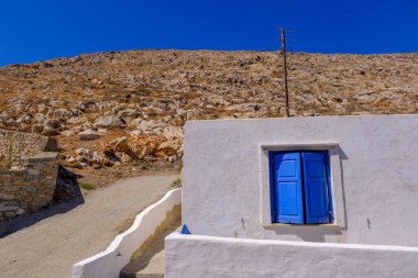 Piros Adası 'nda mavi pencereli, bembeyaz bir evin cephesi