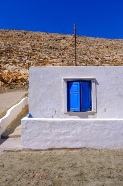 Piros Adası 'nda mavi pencereli, bembeyaz bir evin cephesi