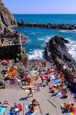 Manarola, IT - 26 Temmuz 2023: Manarola Limanı 'nda güneşlenen insanlar