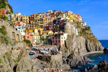 Manarola, IT - 26 Temmuz 2023: Manarola köyünde altın saat boyunca renkli evler