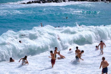 Monterosso al Mare, IT - 25 Temmuz 2023: İnsanlar sahilde büyük dalgaların tadını çıkarıyor