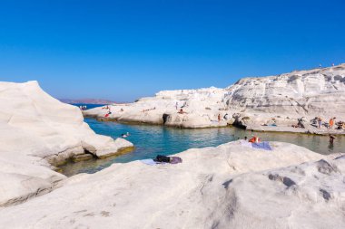 Milos, GR - 28 Eylül 2024: Sarakiniko plajında güneşlenen insanlar