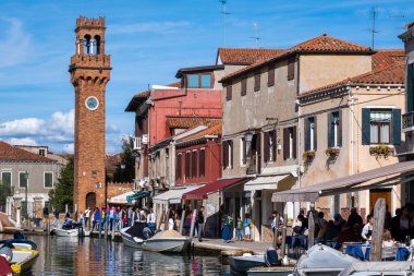Venedik, İtalya - 12 Ekim 2024: Torre dellOrologio, tarihi bir kırmızı tuğlalı saat kulesi Murano 'nun sakin kanalları üzerinde yükselir ve zengin Venedik mirasını yansıtır.