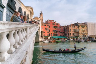 Venedik, İtalya - 12 Ekim 2024: yukarıdan turistler izlerken Rialto köprüsünün altından bir gondol geçiyor