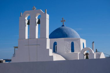 Naoussa 'daki Aziz Athanasius Kilisesi, açık mavi gökyüzünün altında ikonik mavi kubbeleri ve beyaz duvarlarıyla