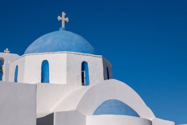 Naoussa 'daki Aziz Athanasius Kilisesi, açık mavi gökyüzünün altında ikonik mavi kubbeleri ve beyaz duvarlarıyla