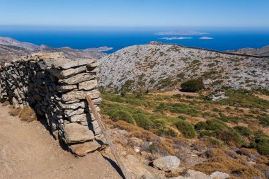 Geleneksel taş duvar, uzak Ege adalarının panoramik manzarasıyla Zeus Dağı 'nda yürüyüş yolunu gösteriyor.