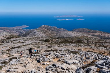 Naxos, Yunanistan - 2 Ekim 2024: Zeus Dağı yürüyüş yolundan geniş panoramik manzara, dağlara, adalara ve derin mavi Ege Denizi 'ne bakan kayalık bir arazide yükselen yürüyüşçüler