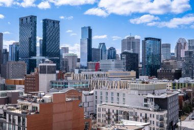Montreal, Kanada - 4 Nisan 2025: Montreal 'in gökyüzünün yüksek açılı görüntüsü, çeşitli bina yükseklikleri ve şehir çatıları parlak, bulutlu bir gökyüzü altında sergileniyor