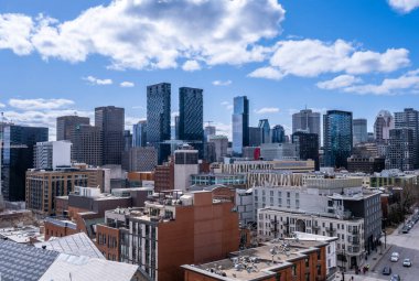 Montreal, Kanada - 4 Nisan 2025: Montreal 'in gökyüzünün yüksek açılı görüntüsü, çeşitli bina yükseklikleri ve şehir çatıları parlak, bulutlu bir gökyüzü altında sergileniyor