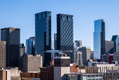 Montreal, Kanada - 4 Nisan 2025: Montreal ufuk çizgisi içindeki Maestria Condominiums kuleleri, açık mavi gökyüzüne karşı eşsiz mimarilerini sergiliyor