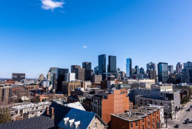 Montreal, Kanada - 4 Nisan 2025: Montreal 'in çeşitli gökdelenlerinin geniş bir görüntüsü, tarihi çatıları modern gökdelenlerle birleştirerek berrak bir yay gökyüzü altında