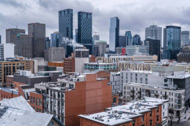 Montreal, Kanada - 4 Nisan 2025: Montreal Maestria Kuleleri ile şehir manzarası, bulutlu gökyüzü altında, şehir mimarisini ön plana çıkaran çatılar