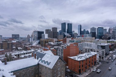Montreal, Kanada - 4 Nisan 2025: Karla kaplı çatıların bulunduğu şehir manzarası bulutlu bir gökyüzü altında